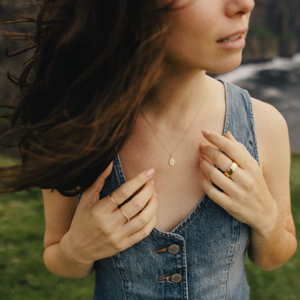 A girl wearing a denim vest and a gold necklace