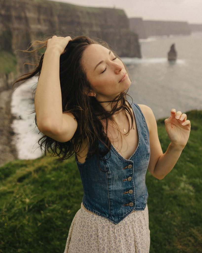 A girl at the Cliffs of Moher with her hair blowing in the wind