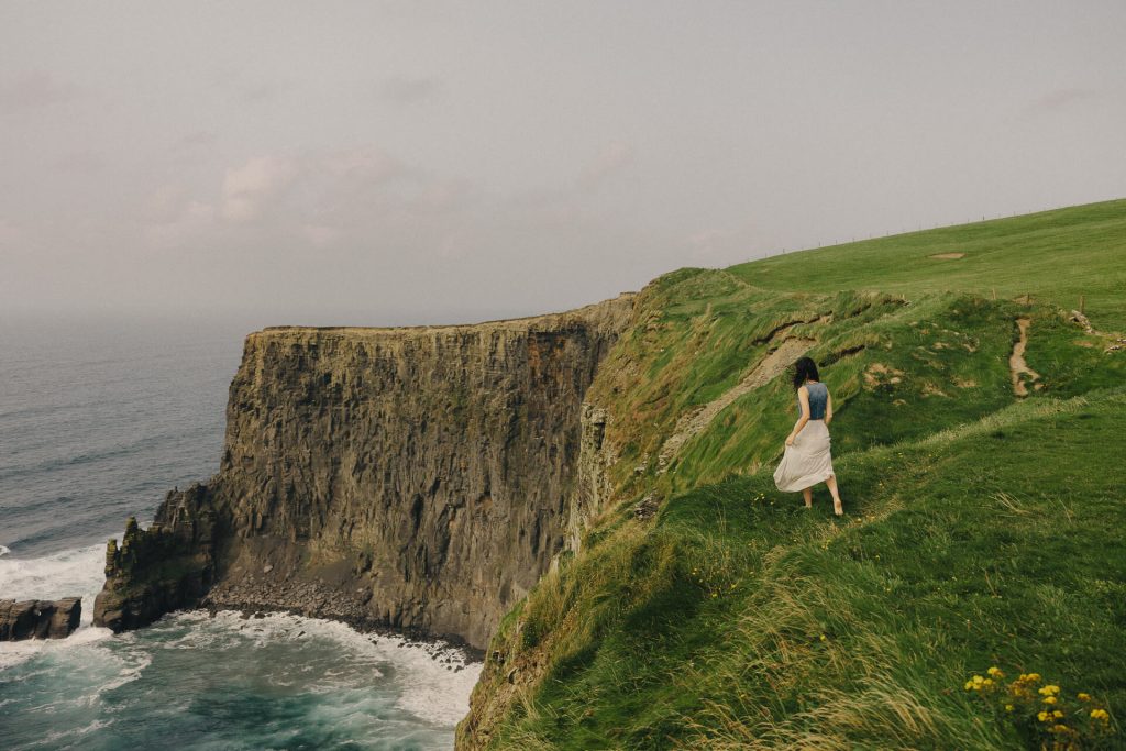 Girl standing at the edge of The Cliffs of Moher in Ireland
