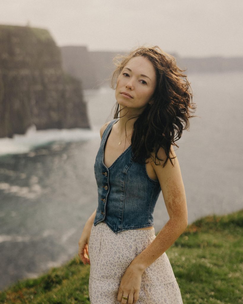 A girl wearing a denim vest and white maxi skirt
